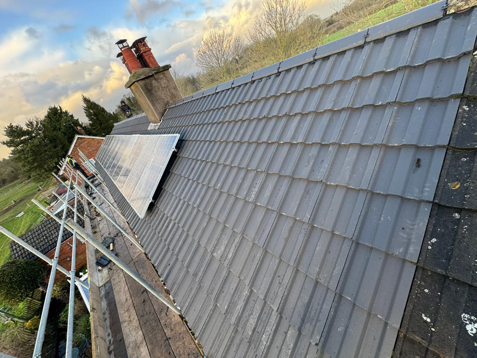 Completed grey tiled roof with chimney and solar panels